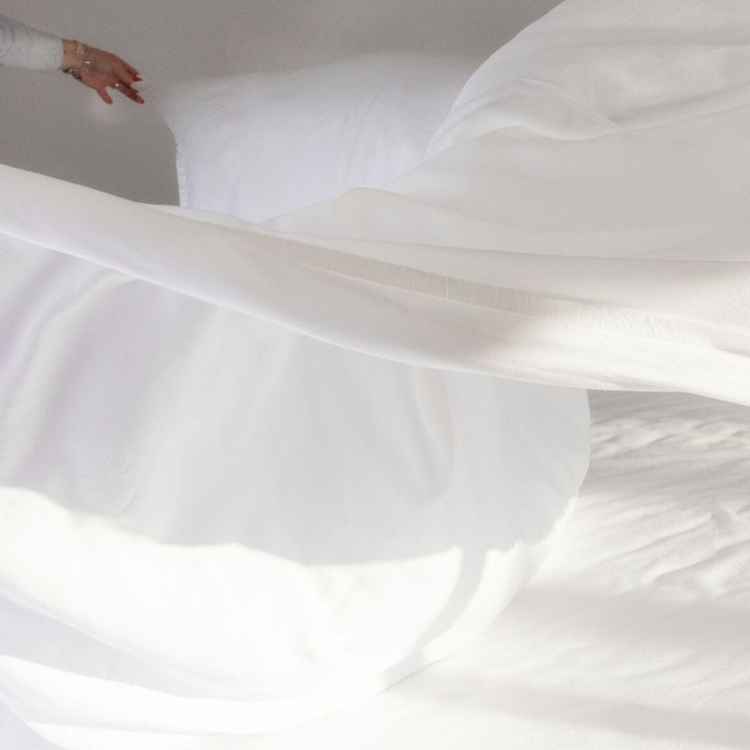 Person making the bed with luxury bed sheets